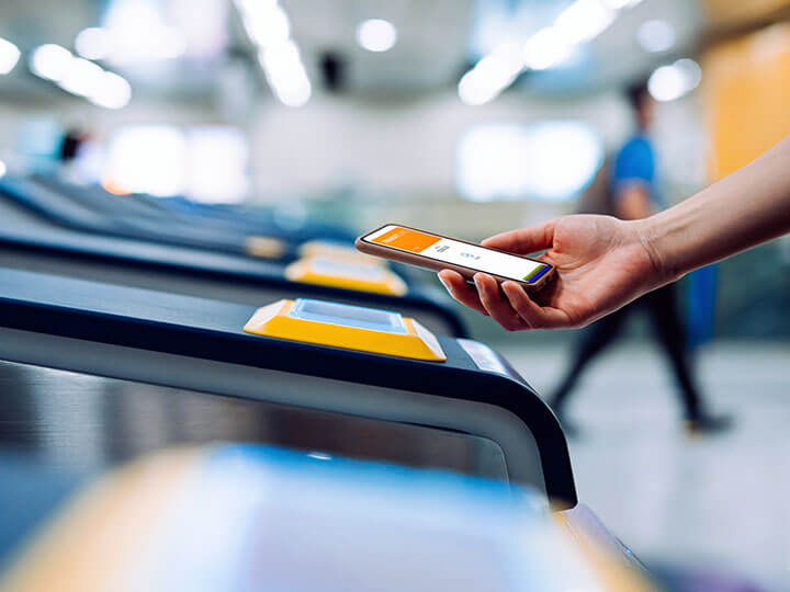 Individual checking in at subway station with smartphone using NFC technology for contactless payment for subway ticket