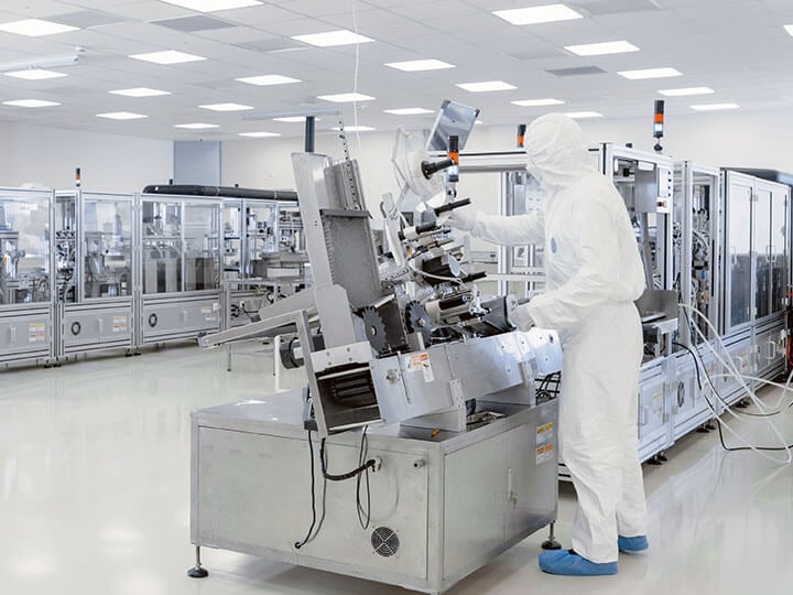 Sterile Manufacturing Laboratory with Scientists in white protective suits using machinery, computers and microscopes for research